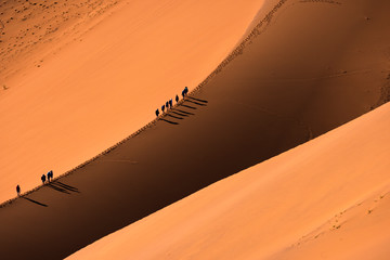 Aerial view group of Traveler walking on the sand dune in the desert and sun gradually create...
