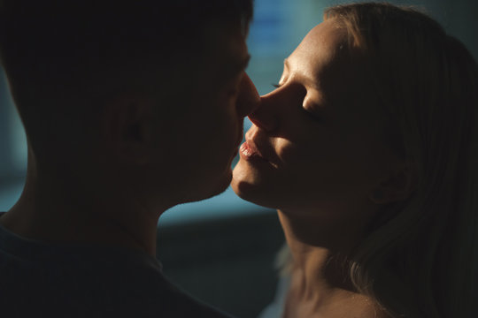 Close up side view portrait of a beautiful young couple smiling before kissing at their home in night.