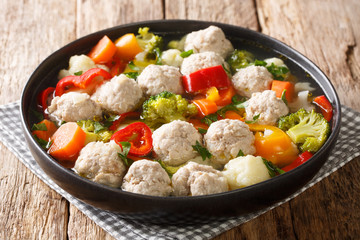 Broth with chicken meatballs and vegetables close-up in a plate. horizontal