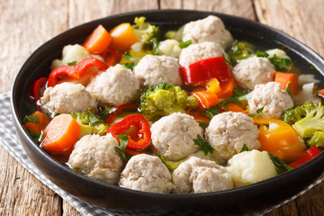 Homemade soup with meatballs, broccoli, pepper, cauliflower, potatoes and carrots close-up in a plate. horizontal