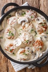meatballs with mushrooms in a creamy sauce with herbs and garlic close-up in a pan. Vertical top view