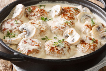 Hot meatballs with mushrooms served in creamy cheese sauce with thyme close-up in a pan. horizontal