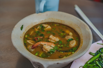 River prawn spicy soup, thai food called Tom Yum Kung in bowl on dining table.
