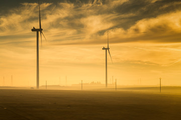 Silhouette of a windmills and electricity poles captured at sunrise , France