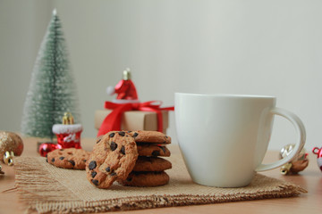 Obraz na płótnie Canvas White mug with Chocolate cookies and gift box on wood table. Christmas holiday concept.