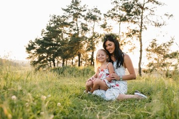 Mother and daughter having fun in the park. Happiness and harmony in family life. Beauty nature scene with family outdoor lifestyle.