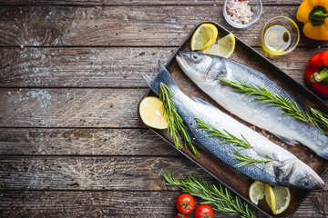 Fresh raw seabass and ingredients for cooking. Two fish seabass with lemon, spices and herbs on...