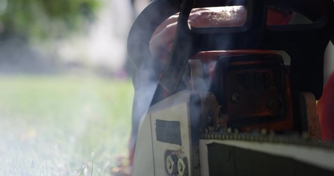 Pull starting chainsaw as smoke comes out of 2 stroke gas engine - close up