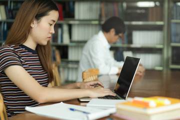 female asian student studying and reading book in library
