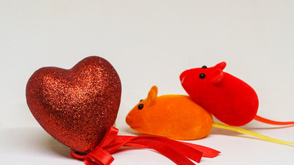 Saint Valentine's day. A pair of toy mice have sex next to a decorative heart.