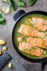 Grilled Salmon with spinach and garlic cream sauce in a frying pan, top view