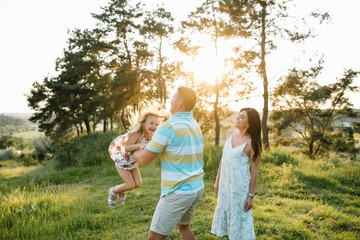 Fototapeta premium Happy family of three persons walking the grass in the park.
