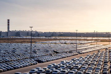 New cars parked in a distribution center on a cloudy rainy day in the autumn, a car factory....