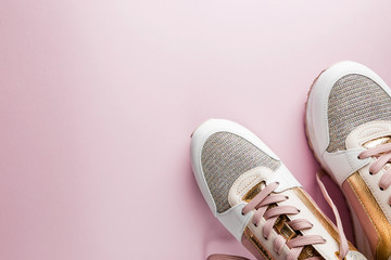 Fashion blog look. White women's sneakers with pink and gold color on pink background. Flat lay, top view beauty female background.