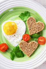Fried egg and two slices of bread in the shape of a heart. Romantic Breakfast for Valentine's day.