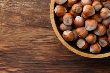 Hazelnuts in wooden bowl on textured background