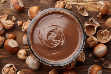 Chocolate spread with nuts on wooden background