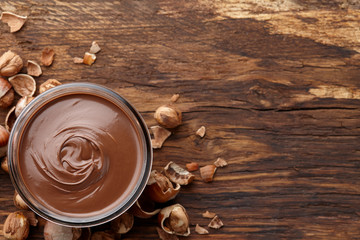 Chocolate spread with nuts on wooden background
