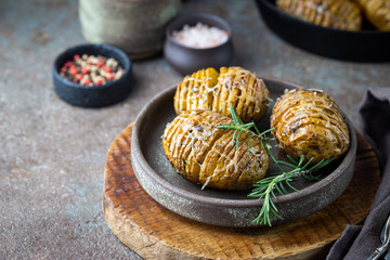Baked hasselback potatoes with cheese, garlic and greens