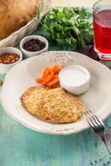 homemade cod fritters with sour cream sauce and carrot and glass of red drink on blue wooden table