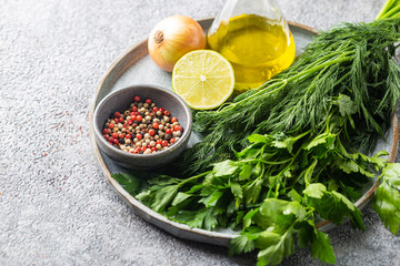 Fragrant fresh parsley and dill with pepper peas, onion and lime arranged on plate over gray background.