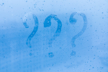 The three question marks picture or figure on the blue evening or morning window glass with drops 