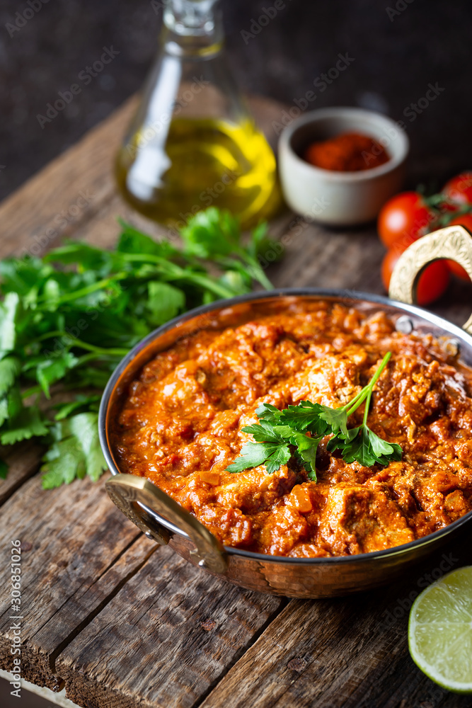 Wall mural Chicken meat with tikka masala sauce, spicy curry food in iron copper pot with seasonings