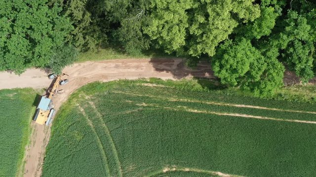 Road leveling motor grader on bad farm road at work, aerial view