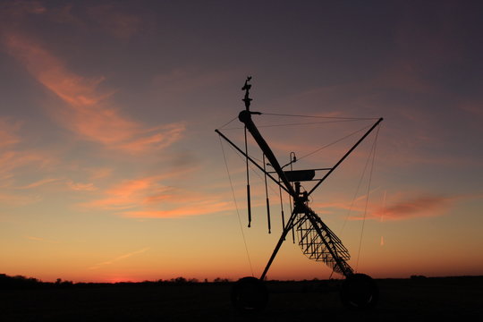 Irragation System at Sunset with a Colorful sky by a farm field.