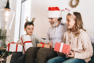 Happy grandfather giving Christmas gifts to his grandkids