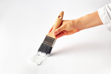 Female hand painting with brush wall surface in white color. Minimalist home repair concept.