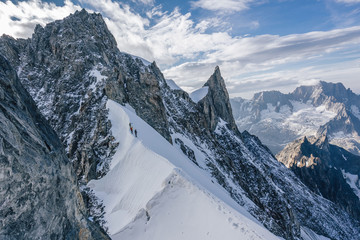 Climbers or alpinist on a knife sharp ridge of an alpine peak or summit of Aiguille du Rochefort....