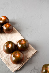 Kumato tomatoes on a gray surface, low angle view. Copy space.