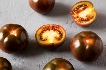 Kumato tomatoes on a gray background, low angle view.