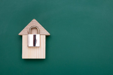 Fototapeta na wymiar lock and wooden toy house on green chalk board, protection concept, copy space