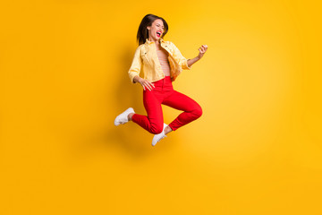 Fototapeta na wymiar Full length body suze turned photo of cheerful rude excited crazy overjoyed woman rejoicing in jumping playing imagine guitar in red pants isolated vivid color background