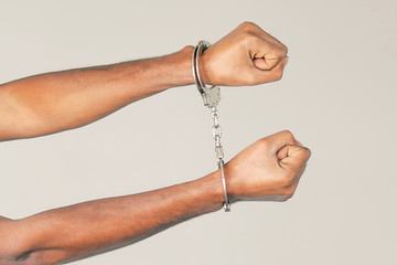Close-up hands arrested african man. African hands in handcuffed isolated on gray background....