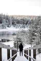Man in the end of a snowy stairway. Forest and a lake located in Ogre, Latvia - on a snowy Winter day