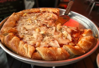 Closeup shot of a giant pizza with thick crust, minus one big slice