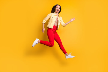 Fototapeta na wymiar Side profile full length body size photo of cheerful pretty cute charming girl running towards shopping mall for sales in red pants isolated vivid color background