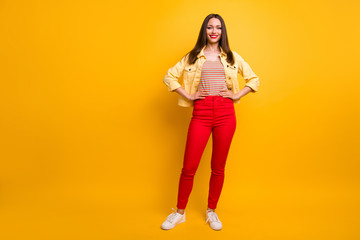 Fototapeta na wymiar Full length body size photo of cheerful positive cute pretty nice girlfriend in trousers holding hands on waist smile toothy white foot wear isolated vivid color background