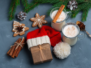 Traditional Christmas homemade drink eggnog on the table with Christmas tree branches and gift box in Santa hat