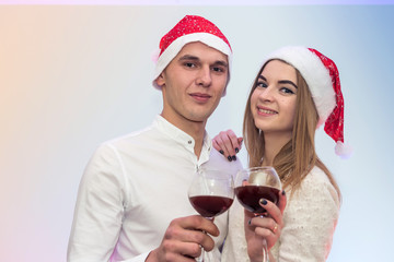 Happy, young couple with wine glasses and santa hats celebrating St. Valentine's Day