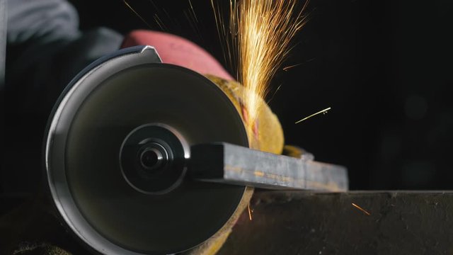 Forge workshop. Smithy manual production. Close up details of sparks, industrial worker using angle grinder and cutting steel. The blacksmith makes iron products for manufacture of fireplaces, stoves.