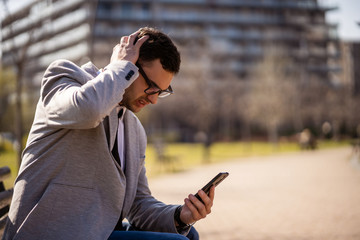 Young businessman is using smartphone in park.