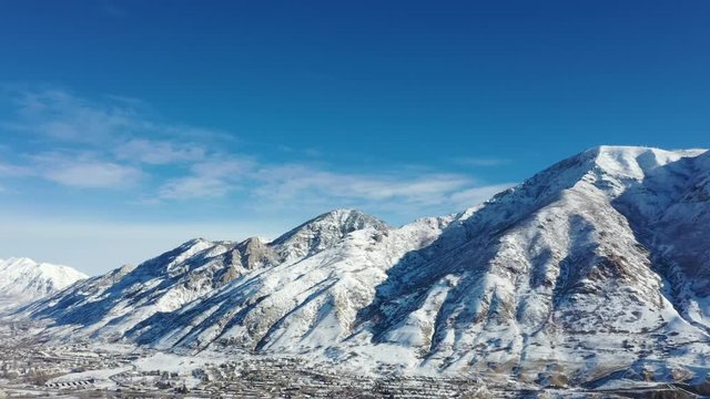 Panning aerial 4k video clip of Buckley Mountain in Provo Utah, covered in snow on a clear winter day with blue sky