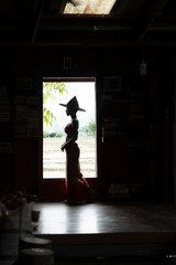 Silhouette Thai woman standing at wooden house window over rice field paddle farm background