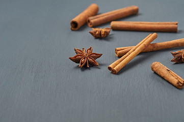 Cinnamon sticks near stars of anise lies on dark scratched desk on kitchen. Space for text