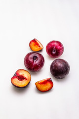 Ripe large purple plums. Fresh whole fruits, half sliced, seeds. Isolated on white background