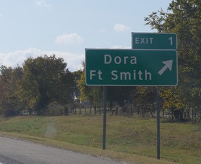 Road signs with directions to Dora and Fort Smith, Arkansas.